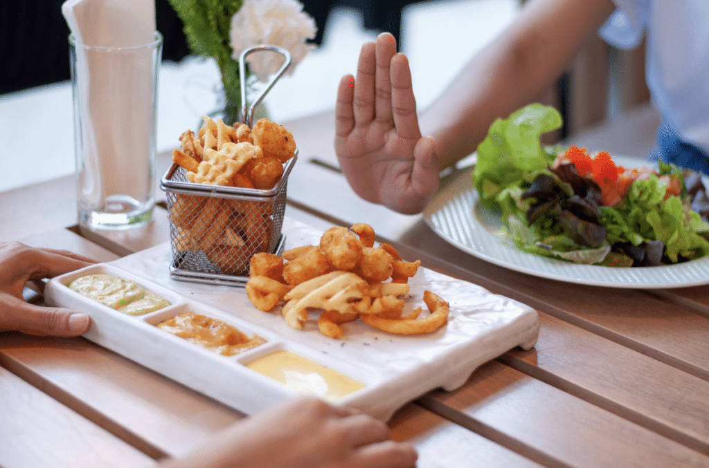 dietary trends: hand refusing fried food at restaurant dining table